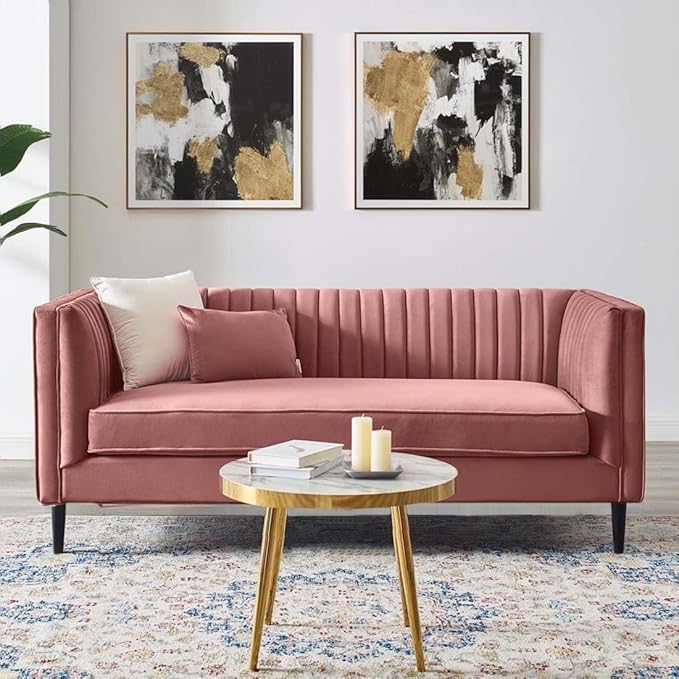 Pink sofa inside living room with 2 pillows, a table 